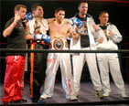 Los combatientes y sus entrenadores posan sobre el ring donde tuvo lugar el combate.
